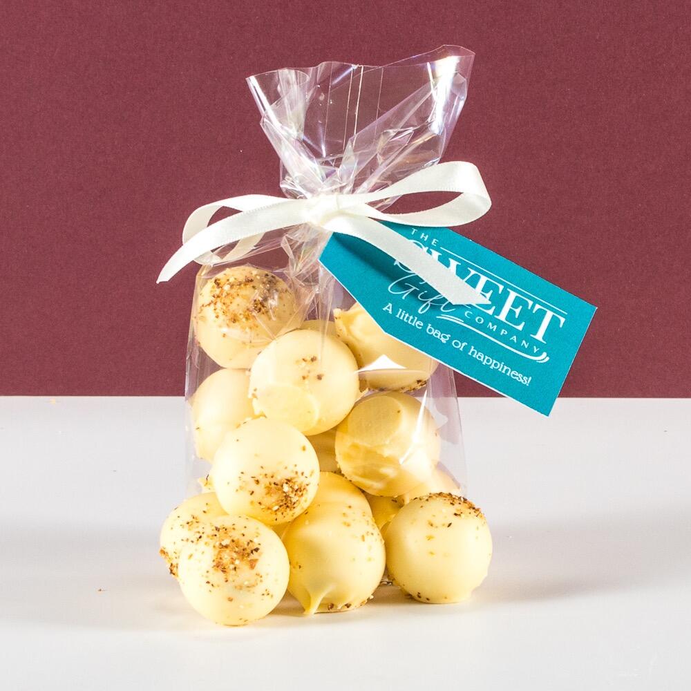 A gift bag of Lemon Cheesecake White Chocolate Truffles Product with a light blue Sweet Gift Company tag and white ribbon
