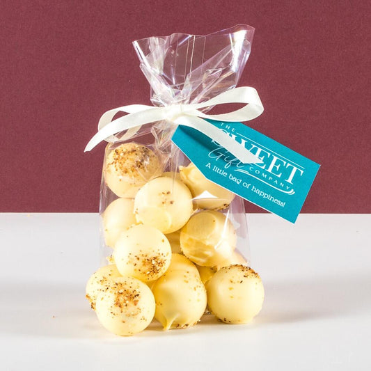 A gift bag of Lemon Cheesecake White Chocolate Truffles Product with a light blue Sweet Gift Company tag and white ribbon
