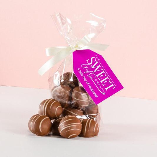 A gift bag of Marc de Champagne Milk Chocolate Truffles with a pink Sweet Gift Company tag and white ribbon